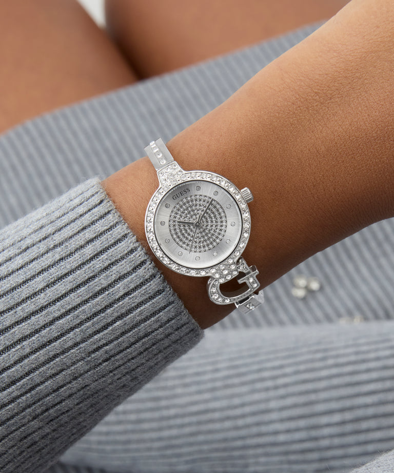 Silver watch with glitz face on a wrist against a gray background