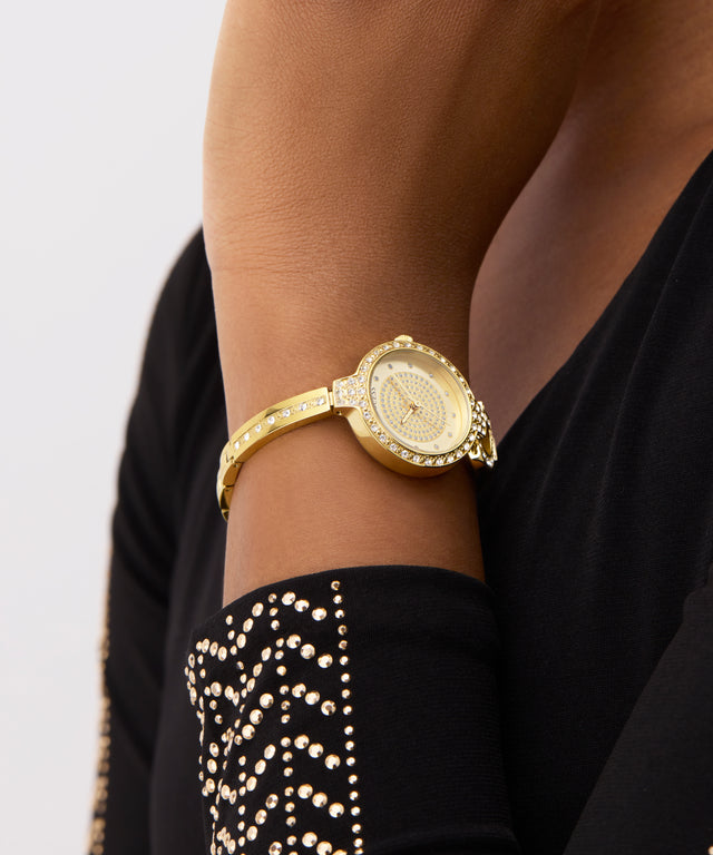 GUESS Ladies Gold Tone Analog Watch on a wrist with a black outfit