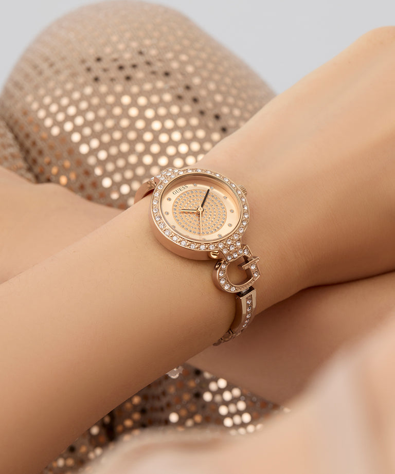 GUESS Ladies Rose Gold Tone Analog Watchwith diamond accents on a wrist against a neutral background
