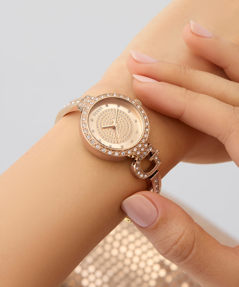 GUESS Ladies Rose Gold Tone Analog Watch with diamond accents on a wrist against a light background