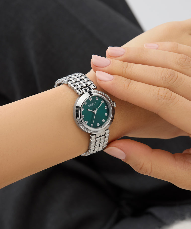 GUESS Ladies Silver Tone Analog Watch with a green face on a wrist against a black background