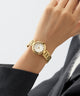 GUESS Ladies Gold Tone Analog Watch on a person's wrist with a plain background