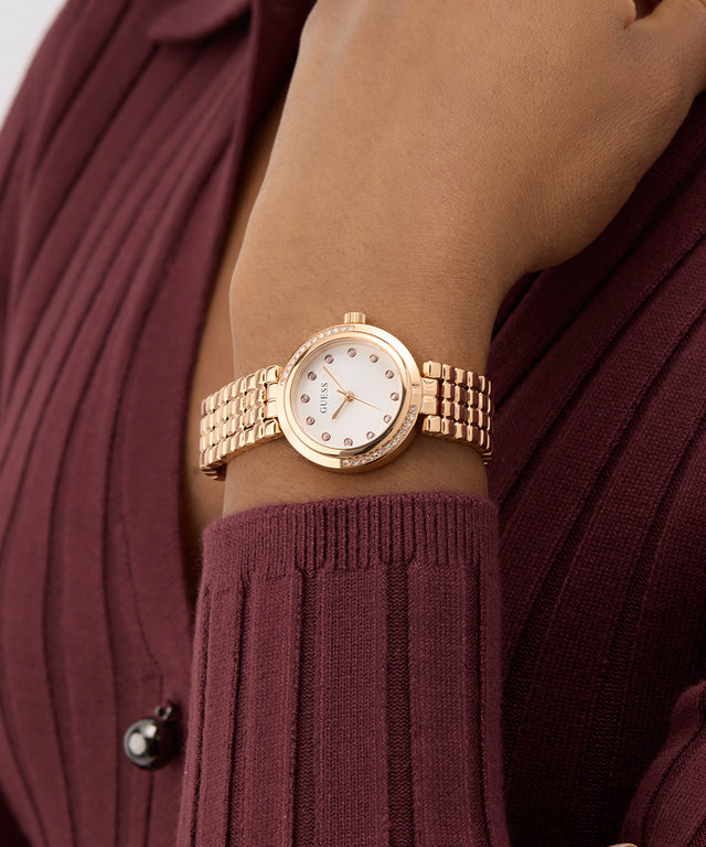 GUESS Ladies Rose Gold Tone Analog Watch on a wrist with a maroon background