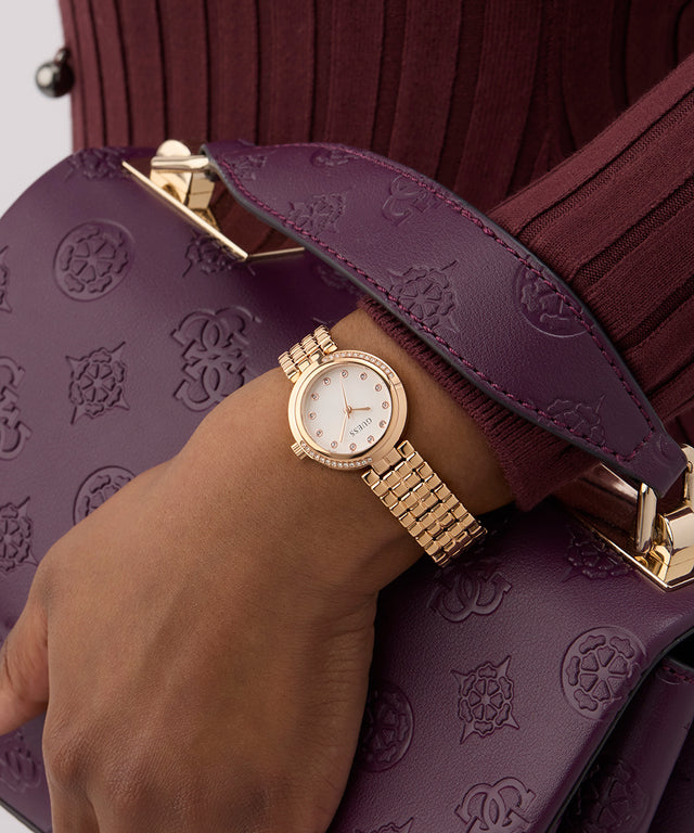 GUESS Ladies Rose Gold Tone Analog Watch on a wrist with a purple textured handbag