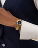 Gold watch on a wrist with a dark suit and white shirt
