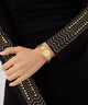 Gold GUESS Ladies Gold Tone Analog Watch on a hand with black garment featuring gold embroidery