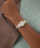 Silver GUESS Ladies Pixie 2-Tone Analog Watch on a wrist with a textured background