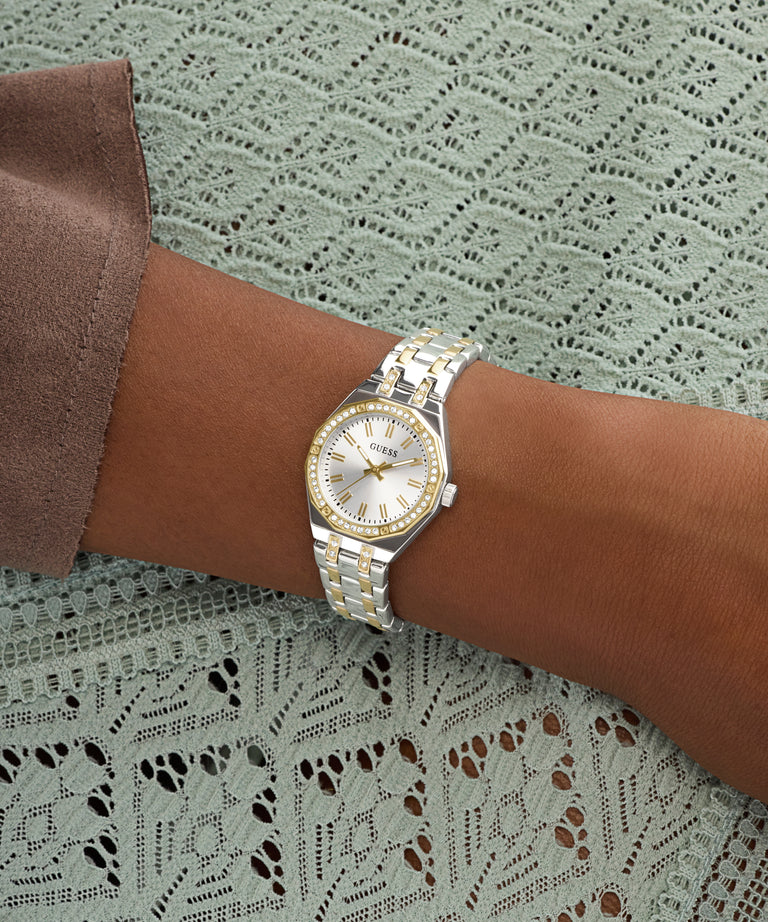 Silver GUESS Ladies Pixie 2-Tone Analog Watch on a wrist with a textured green background