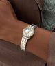 Two-tone GUESS Ladies Pixie 2-Tone Analog Watch on a wrist with a brown jacket