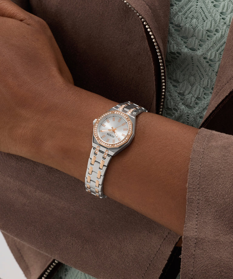 Silver watch with a two-tone band on a wrist, wearing a brown jacket.