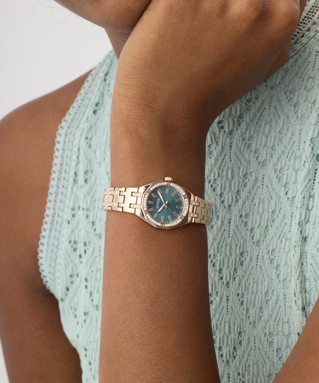Rose gold watch with green face on a wrist against a light green textured background