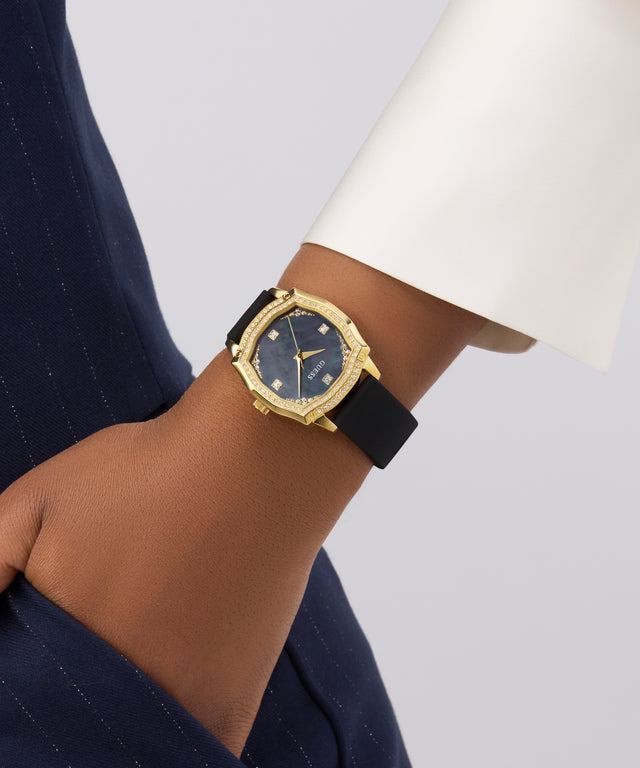 GUESS Ladies Black Gold Tone Analog Watch with black strap on a wrist against a neutral background