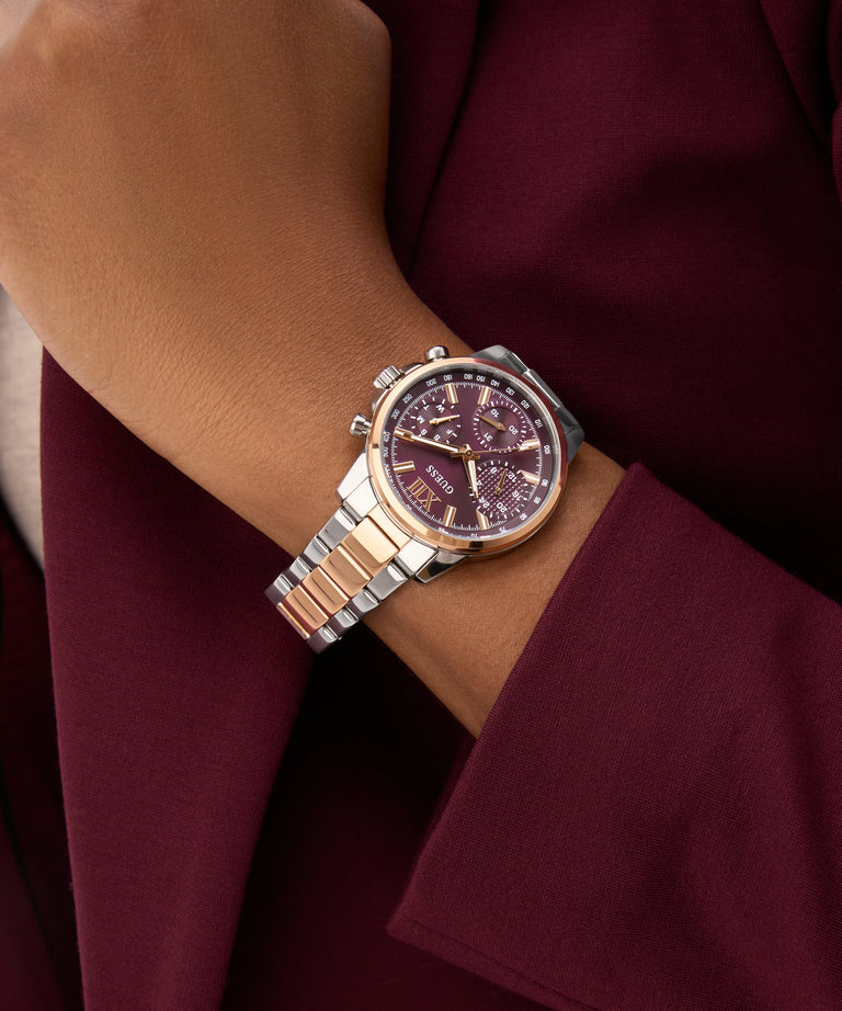 Close-up of a wrist wearing a sGUESS Ladies 2-Tone Multi-function Watch with a cherry face.