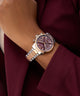 Close-up of a wrist wearing a sGUESS Ladies 2-Tone Multi-function Watch with a cherry face.