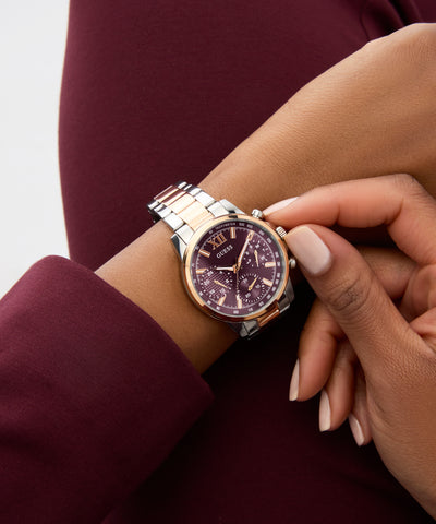 Close-up of a wrist wearing a silver and rose gold watch with a cherry dial.