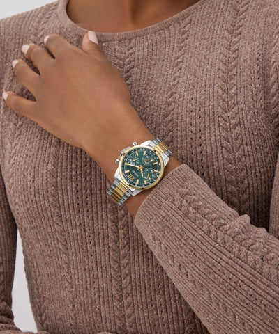 Person wearing a gold and green GUESS Ladies 2-Tone Multi-function Watch on a brown sweater