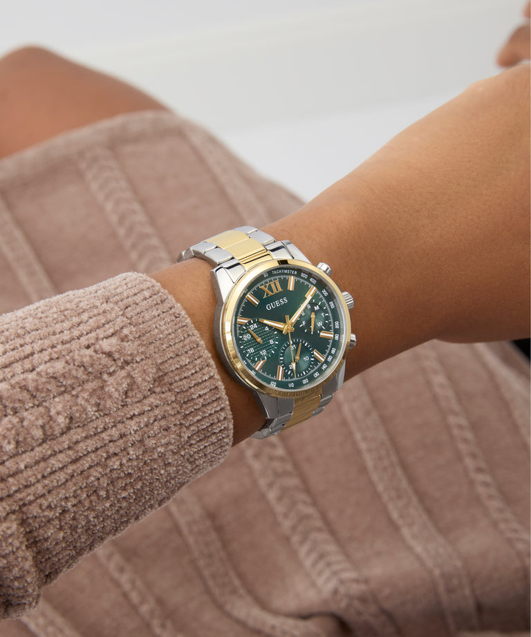 Close-up of a person wearing a Guess GUESS Ladies 2-Tone Multi-function Watch on a neutral background