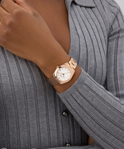 Rose gold GUESS Ladies Rose Gold Tone Date Watch on a wrist with a gray sweater