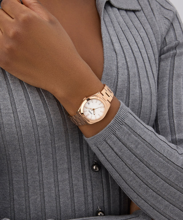 Rose gold GUESS Ladies Rose Gold Tone Date Watch on a wrist with a gray sweater