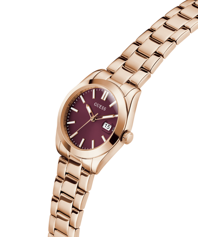 GUESS Ladies Rose Gold Tone Date Watch with a burgundy face on a white background lifestyle
