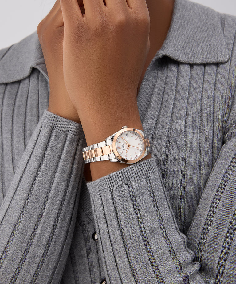 Rose gold GUESS Ladies 2-Tone Date Watch on a wrist with a gray ribbed sweater
