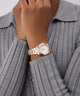 Rose gold GUESS Ladies 2-Tone Date Watch on a wrist with a gray ribbed sweater