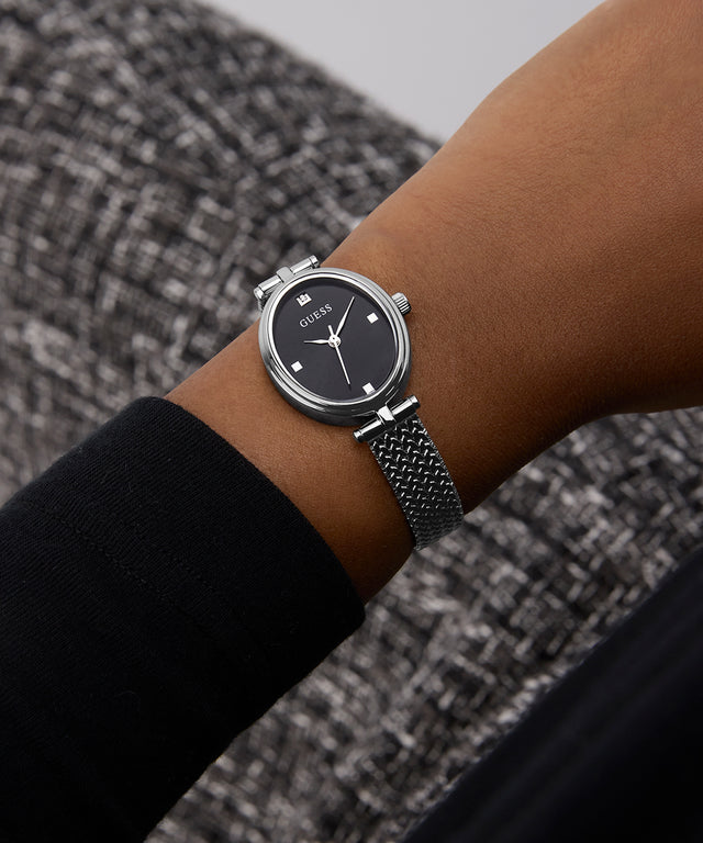 GUESS Ladies Silver Tone Analog Watch on a wrist with a textured gray background