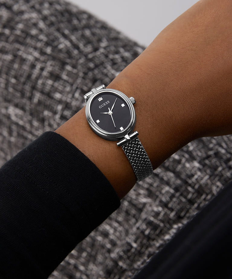 GUESS Ladies Silver Tone Analog Watch on a wrist with a textured gray background