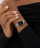 GUESS Ladies Silver Tone Analog Watch on a wrist with a blurred background