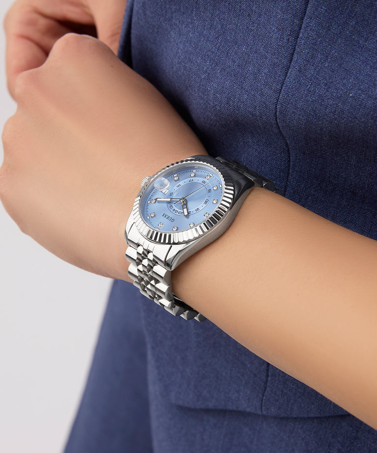 Silver watch with a blue face on a person's wrist against a blue background GW0936L1