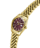 Gold-tone wristwatch with a fluted bezel, gold link bracelet, and a maroon dial featuring diamond hour markers and a date window. lifestyle