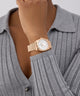 GUESS Ladies Rose Gold Tone Multi-function Date Watch on a wrist with a gray ribbed sweater