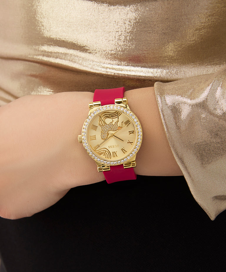 Gold GUESS Ladies Limited Edition Lunar New Year Red Gold Tone Analog Watch with a red strap worn on a wrist against a gold fabric background
