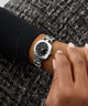 Silver GUESS Ladies Black Silver Tone Analog Watch on a wrist with a textured black and white background