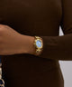 Gold watch on a wrist with a brown sweater