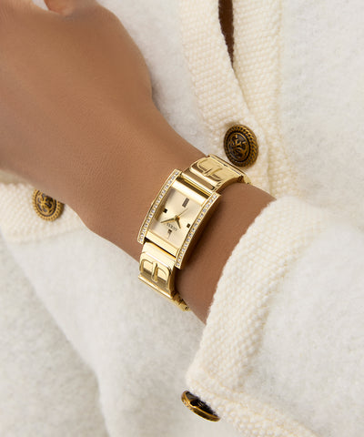 GUESS Ladies Gold Tone Analog Watch on a wrist with a white textured background