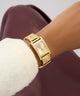 GUESS Ladies Gold Tone Analog Watch on a wrist with a blurred background