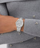 GUESS Ladies Silver Tone Analog Watch on a wrist with a gray ribbed sweater