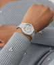 GUESS Ladies Silver Tone Analog Watch on a person's wrist with a gray textured background