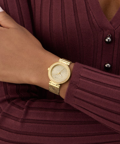 GUESS Ladies Beige Gold Tone Analog Watch on a wrist with a maroon ribbed sweater