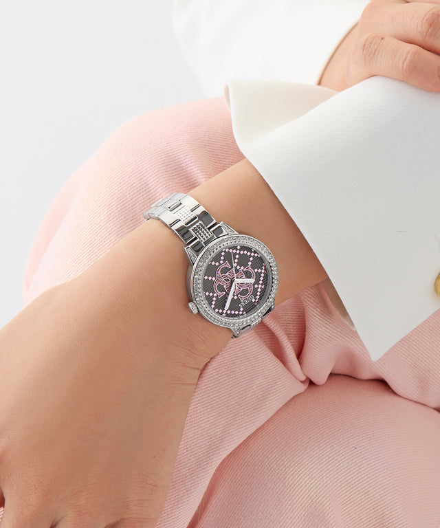 Silver watch with pink face on a person's wrist against a light background GUESS Ladies Silver Tone Analog Watch