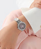 Silver watch with pink face on a person's wrist against a light background GUESS Ladies Silver Tone Analog Watch