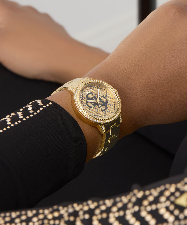 GUESS Ladies Gold Tone Analog Watch on a wrist with a blurred background