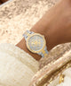 Gold and silver watch on a wrist with a textured background