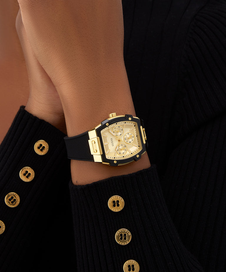 Gold watch on a wrist with a black strap against a dark background GUESS Ladies Black Gold Tone Multi-function Watch GW0945L2