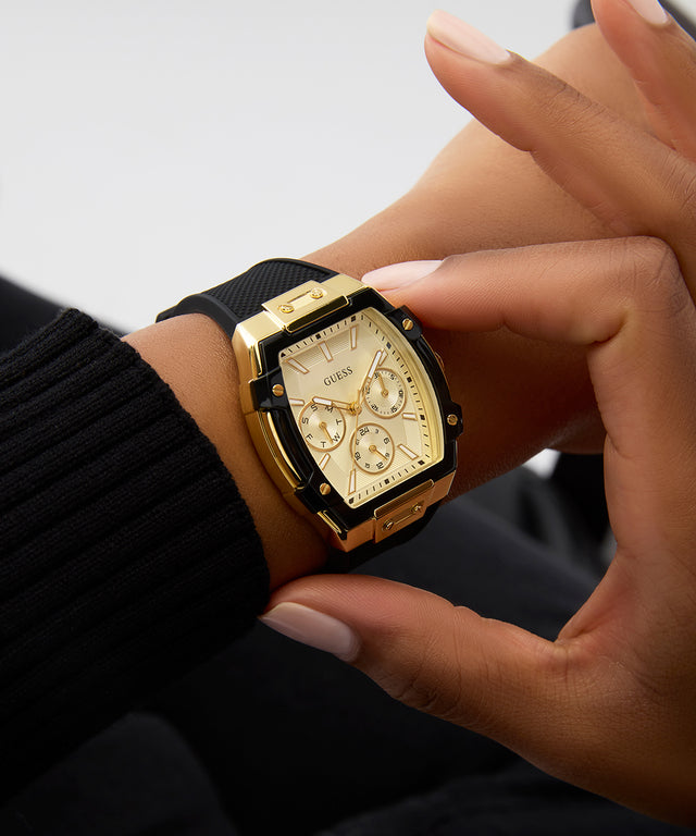 Gold watch with black strap on a wrist against a neutral background