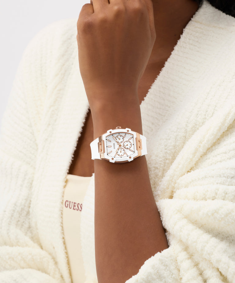 Person wearing a white GUESS Ladies White Rose Gold Tone Analog Watch on a white background