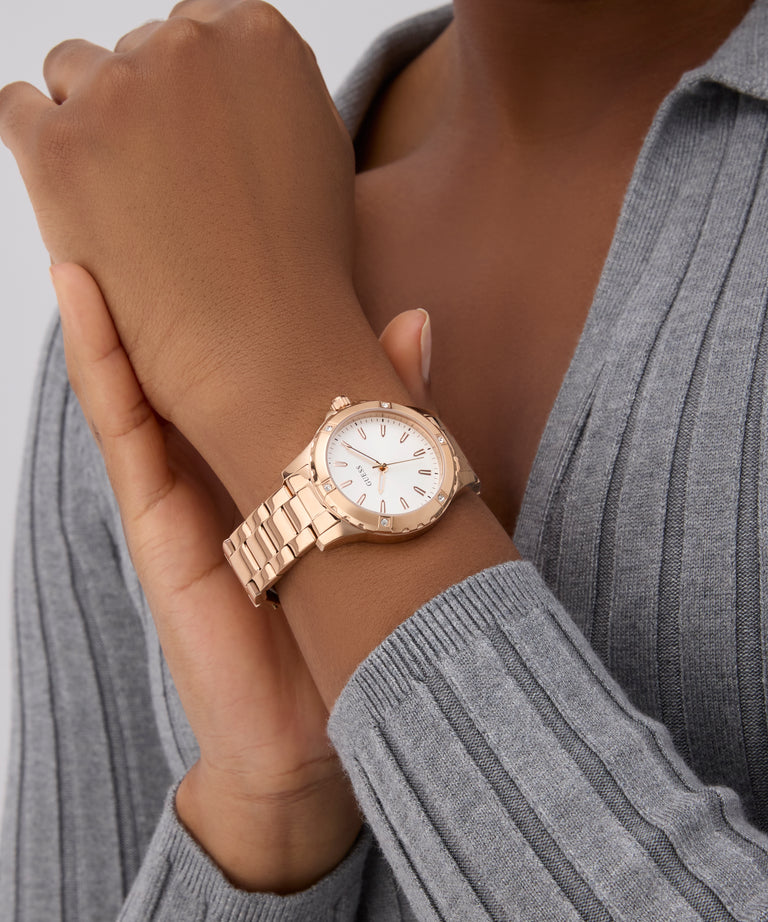 GUESS Ladies Rose Gold Tone Analog Watch on a wrist with a gray sweater