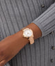 GUESS Ladies Rose Gold Tone Analog Watch on a wrist with a gray ribbed sweater background