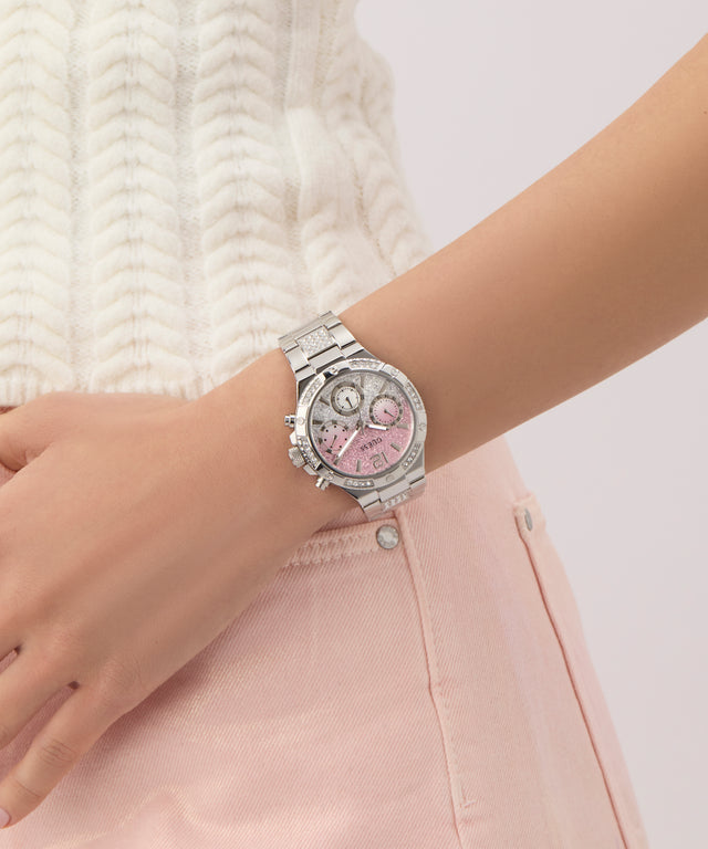 Wrist wearing a silver watch GW0950L1 with a pink face on a light background